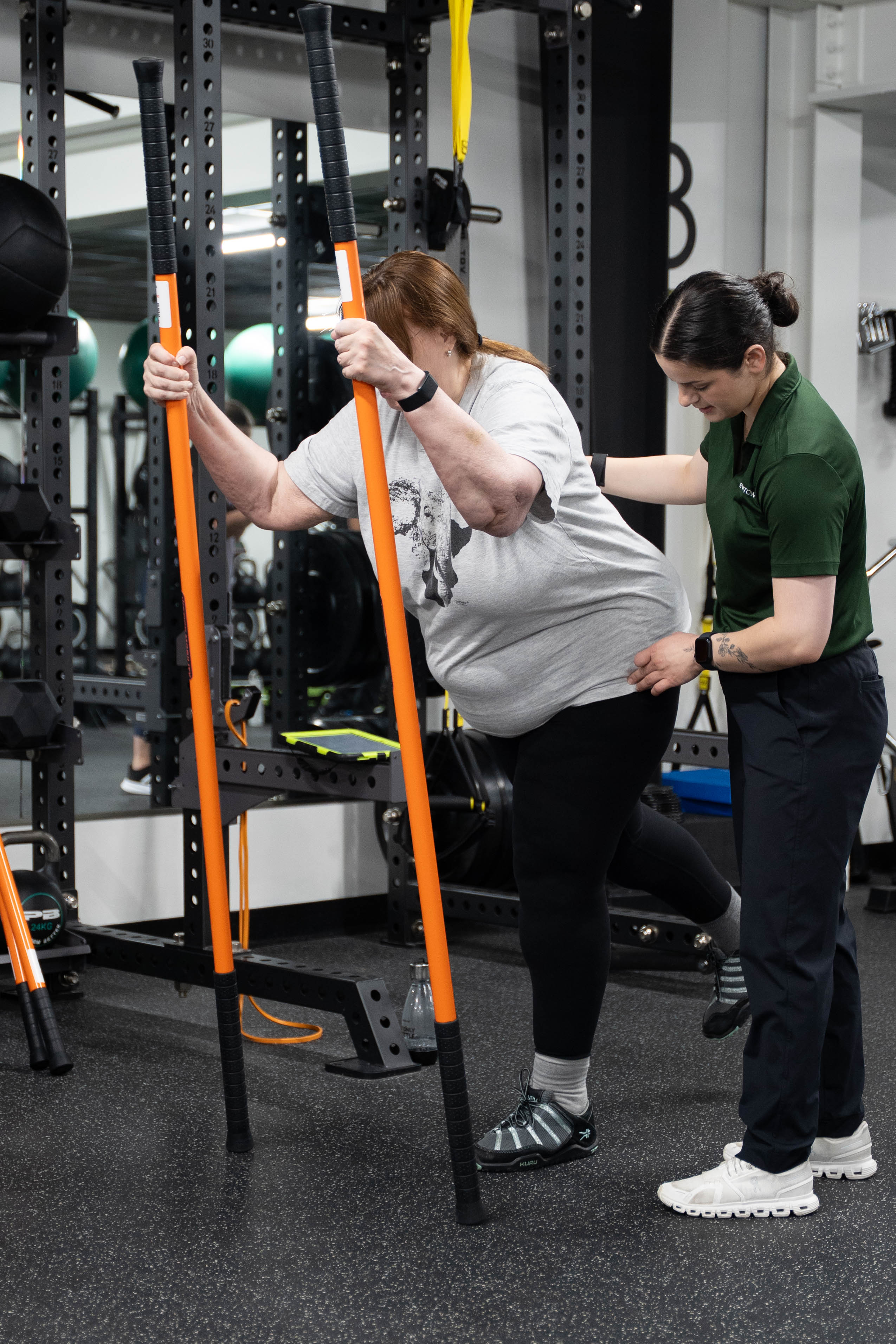 Coach guiding a member through a stick mobility exercise at The Gym Newtown